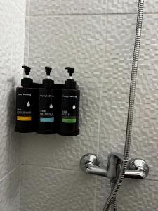 trois bouteilles de shampoing sur une étagère dans une douche dans l'établissement Apartamento matriz, à Póvoa de Varzim