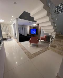 a living room with a staircase with a couch and a television at CasaparkIndaiatuba in Indaiatuba
