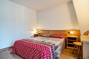 een slaapkamer met een bed met een rood-witte deken bij Giongo Residence Aparthotel 101 in Lavarone