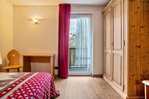 een slaapkamer met een bed en een raam met rode gordijnen bij Giongo Residence Aparthotel 101 in Lavarone