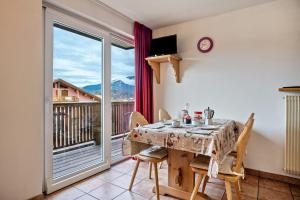 een eetkamer met een tafel en stoelen en een balkon bij Giongo Residence Aparthotel 101 in Lavarone