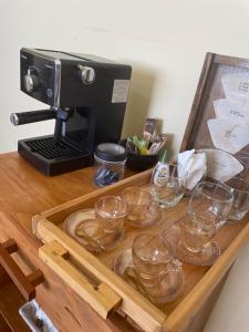 a wooden tray with glasses on a table with a coffee maker at Homeoffice Central 1 quarto 1 cama de casal banheiro privativo in Alfenas