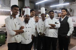 a group of chefs posing for a picture in a kitchen at Hotel Hardik Palacio in Varanasi