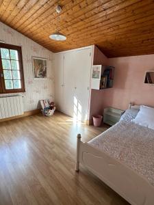 Maison de campagne cosy dans la verdure في Champniers: غرفة نوم بسرير وسقف خشبي
