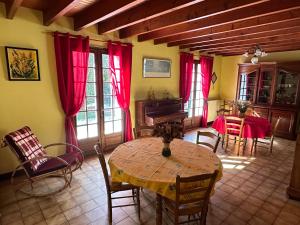 um quarto com uma mesa e cadeiras e cortinas vermelhas em Maison de campagne cosy dans la verdure em Champniers