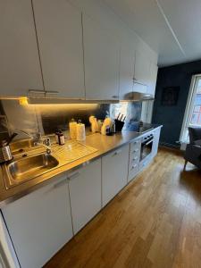 uma cozinha com armários brancos e um lavatório em Super Central 3-bedroom apartment em Oslo