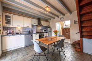una cocina con armarios blancos y una mesa y sillas de madera. en Meublé De Tourisme Acanthe, en Camaret-sur-Mer