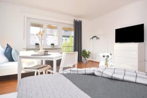 a white living room with a table and a tv at BA02-RI Apartment bei Bamberg in Reckendorf