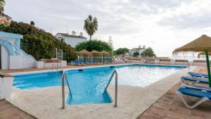 una gran piscina con sillas y sombrillas en Apartment Alhamar Beach Mijas, en Mijas