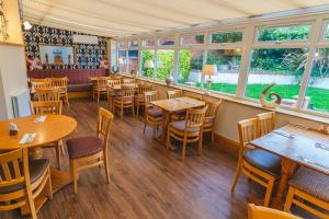 a restaurant with wooden tables and chairs and windows at Eyre arms in Rampton