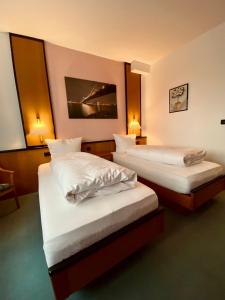 um quarto de hotel com duas camas com lençóis brancos em E&D Hotel Rodgau em Rodgau