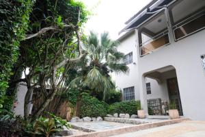 une maison blanche avec un palmier en face dans l'établissement Villa Ayaba, à Abidjan