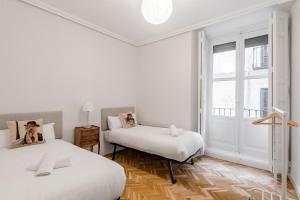 Habitación blanca con 2 camas y ventana en GuestReady - Trendy residence near Plaza Mayor, en Madrid
