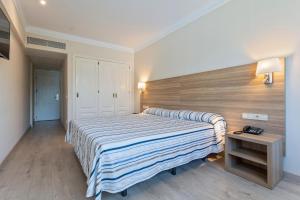 a bedroom with a large bed with a striped blanket at Hotel Best Osuna in Madrid
