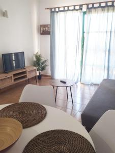 een woonkamer met een tv en een tafel en stoelen bij Las Torres del Castillo 105 in Costa de Antigua