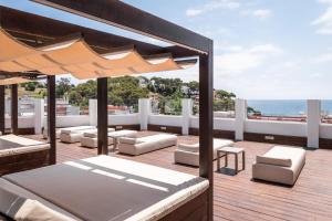 una terraza al aire libre con muebles blancos y sombrilla en ALEGRIA Sun Village en Lloret de Mar