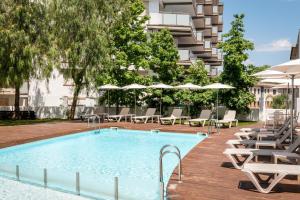 una piscina con sillas y sombrillas junto a un edificio en ALEGRIA Sun Village, en Lloret de Mar