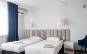 2 łóżka w pokoju z białą pościelą i niebieskim krzesłem w obiekcie B&B HOTEL Piotrków Trybunalski w Piotrkowie Trybunalskim
