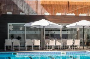 een zwembad met stoelen en parasols naast een gebouw bij ALEGRIA Mariner in Lloret de Mar