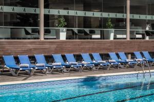 a row of blue lounge chairs next to a pool at ALEGRIA Mariner in Lloret de Mar