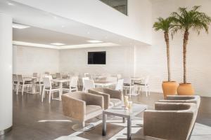 a room with white chairs and tables and palm trees at ALEGRIA Mariner in Lloret de Mar