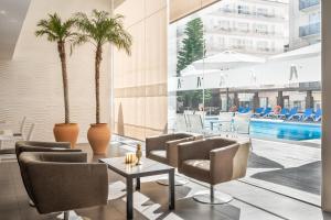 a hotel lobby with chairs and a pool at ALEGRIA Mariner in Lloret de Mar