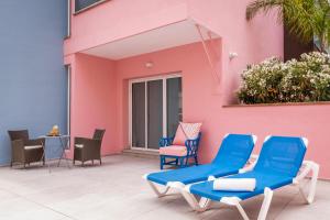 a patio with blue chairs and a pink building at ALEGRIA Mariner in Lloret de Mar