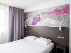 a bedroom with two beds and a painting of a woman at B&B HOTEL Bytom in Bytom