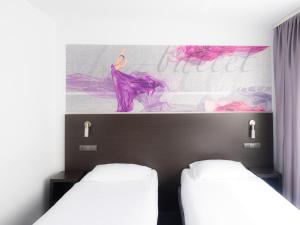 2 camas en una habitación con un cuadro en la pared en B&B HOTEL Bytom en Bytom
