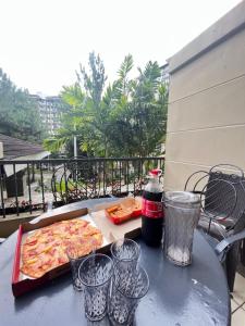 une pizza assise sur une table avec des tasses dans l'établissement AZ Suites 2 bedroom Camella Northpoint, à Davao