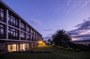 un bâtiment avec un palmier en face dans l'établissement Hotel Altos de la Viña, à San Salvador de Jujuy