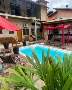 una piscina frente a una casa con sombrillas rojas en Guest House Della Vita, en Ilhabela