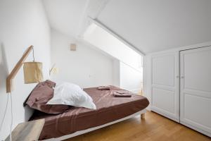 1 dormitorio con cama y pared blanca en T3 Duplex - Vue sur toits & Cité, en Carcassonne