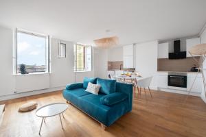 sala de estar con sofá azul y cocina en T3 Duplex - Vue sur toits & Cité en Carcassonne