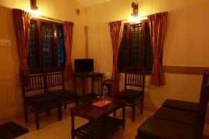 a living room with chairs and a table and a tv at MM Resorts in Yercaud