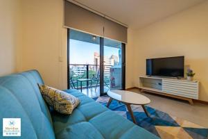 een woonkamer met een blauwe bank en een televisie bij Tribeca del Sol - 501 in Asuncion