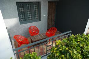 - deux chaises rouges et une table sur un balcon dans l'établissement MM Resorts, à Yercaud