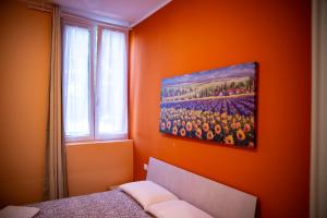 a bedroom with an orange wall with a painting on the wall at Casa Flavia in Rozzano