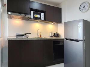 a kitchen with black cabinets and a stainless steel refrigerator at BGC Central Comforts in Manila