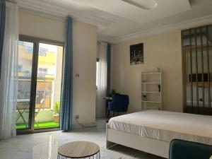 a bedroom with a bed and a table and a window at Le doux refuge in Dakar