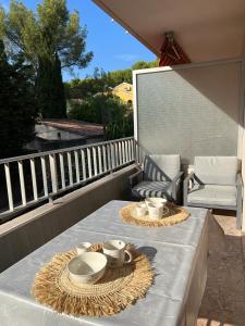 a table with plates and bowls on a balcony at Petit paradis Portissol 400m plage/commerces in Sanary-sur-Mer