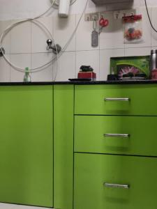 a kitchen with green drawers and green cabinets at Aayushman Homes in Bangalore