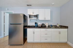 a kitchen with a stainless steel refrigerator and white cabinets at JetPad Tampa Modern studio near Busch Gardens & Airport in Tampa