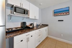 a kitchen with white cabinets and a microwave at JetPad Tampa Modern studio near Busch Gardens & Airport in Tampa