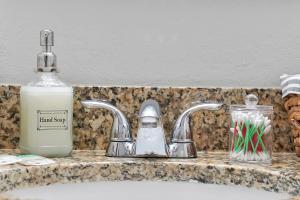 lavabo con botella de jabón y dispensador de jabón en Comfortable private room in Tampa: The Wanderlust en Tampa