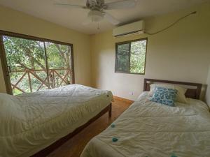 Chepo的住宿－Arrue's Mountain Retreat，一间卧室配有两张床和吊扇