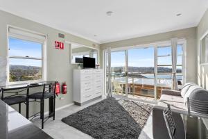 a living room with a desk and a tv and windows at Northern Beaches Surfer's Sanctuary Studio in Deewhy +8 photos