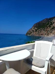 a white chair sitting on a balcony overlooking the ocean at Agia Roumeli Hotel in Agia Roumeli