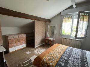 a bedroom with a bed and a dresser and windows at La Chambre Du Voyageur in Soustons