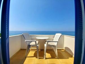 stół i 2 krzesła na balkonie z widokiem na ocean w obiekcie Agia Roumeli Hotel w mieście Ajia Rumeli